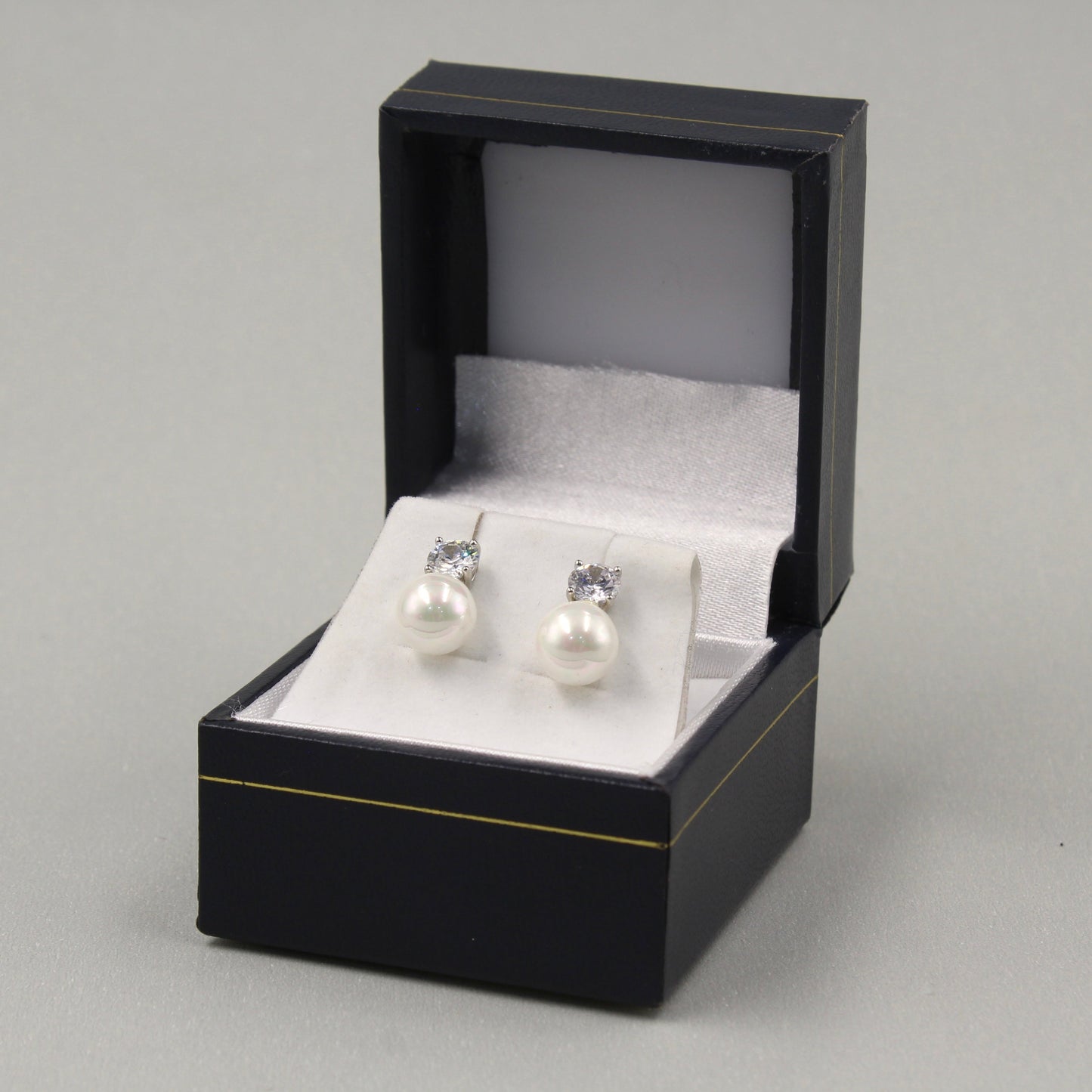 Pendientes de perlas con brillantes pequeños en una caja negra.