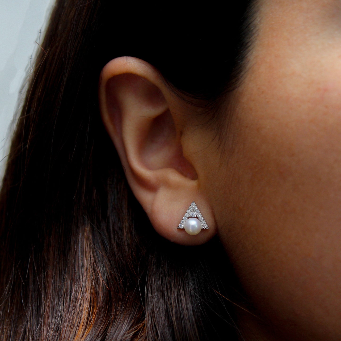 Mujer con aretes en forma de triángulo de zirconia con perla.