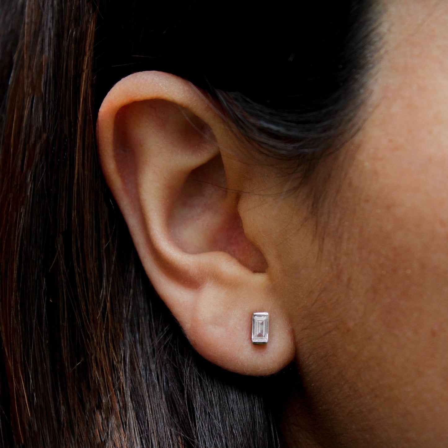 Mujer con aretes en forma de rectángulo pequeño.