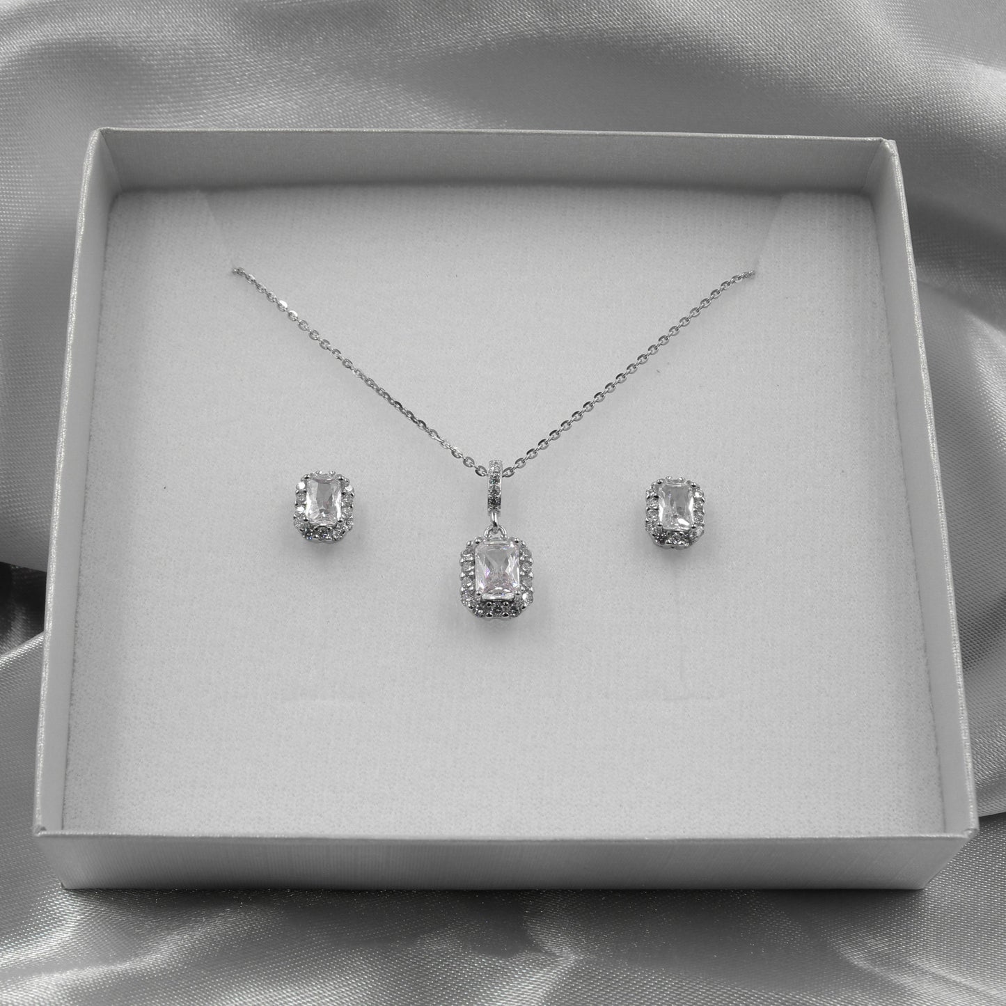 Juego de joyas de plata con cristales ovalados, presentado en una caja elegante.