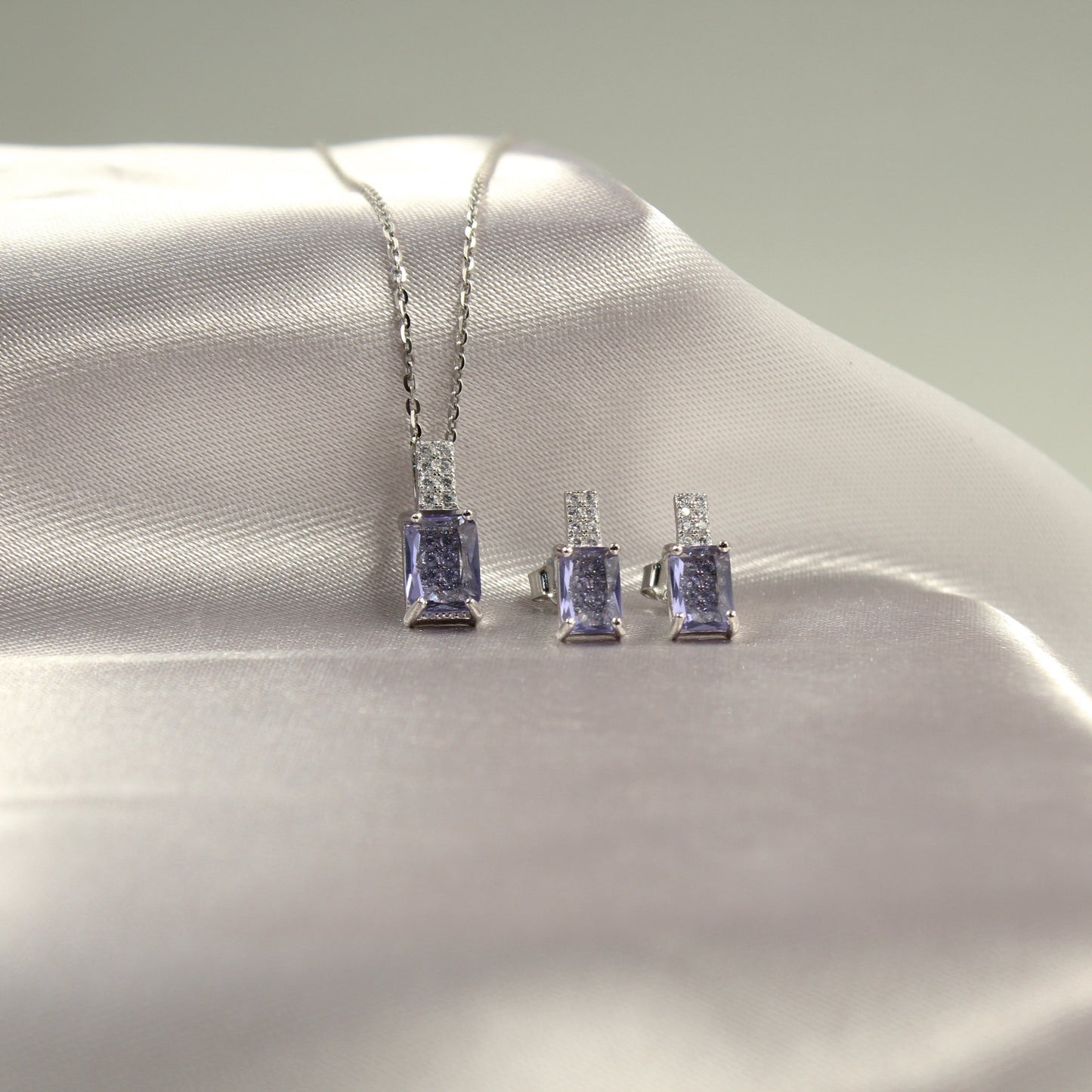 Conjunto de joyería de plata con piedra lila, que incluye un collar y un par de aretes.