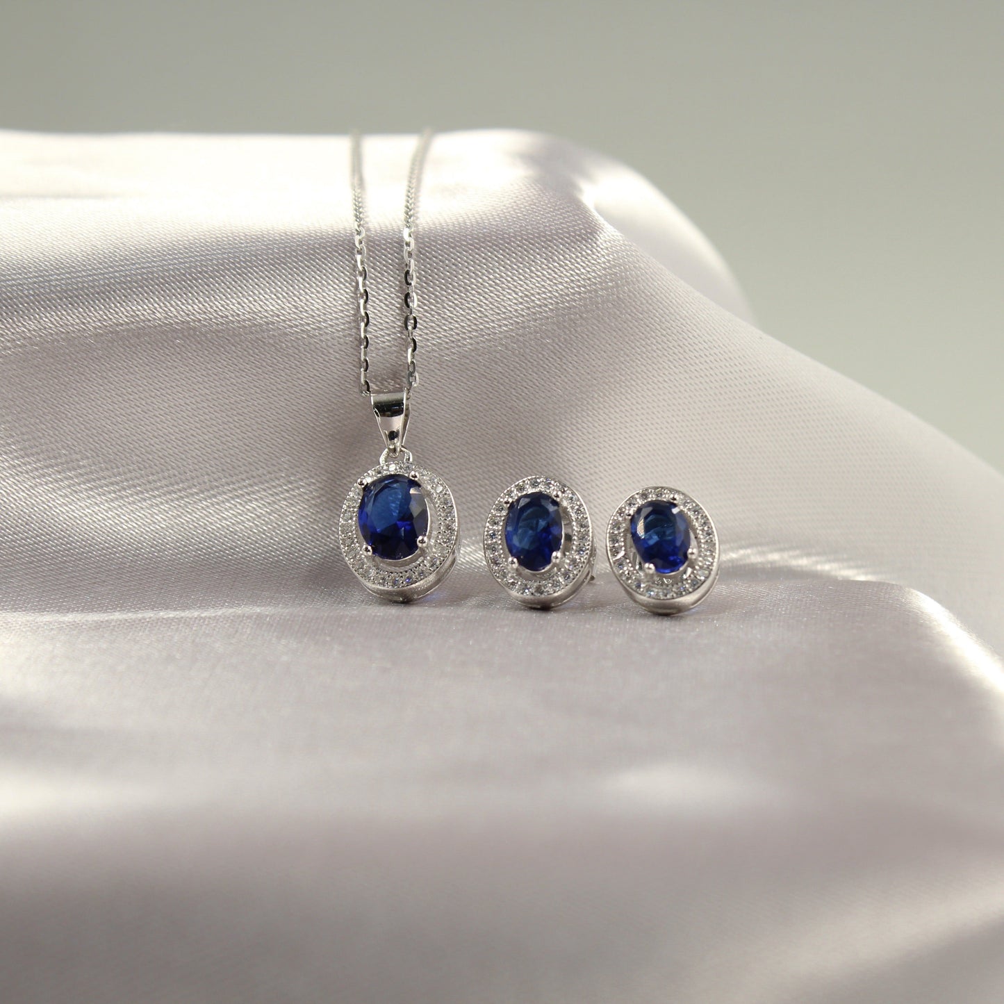 Conjunto de joyería de plata con zafiro azul, que incluye un collar y un par de aretes.