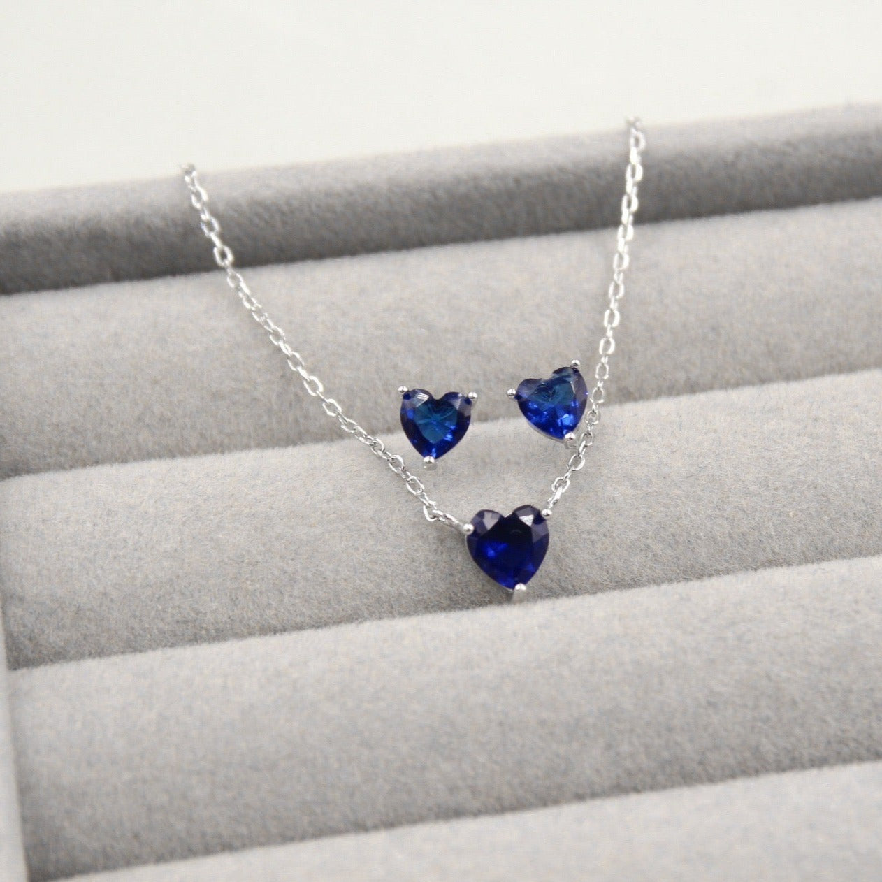 Conjunto de joyería de plata con corazones azules, que incluye un collar y un par de aretes.