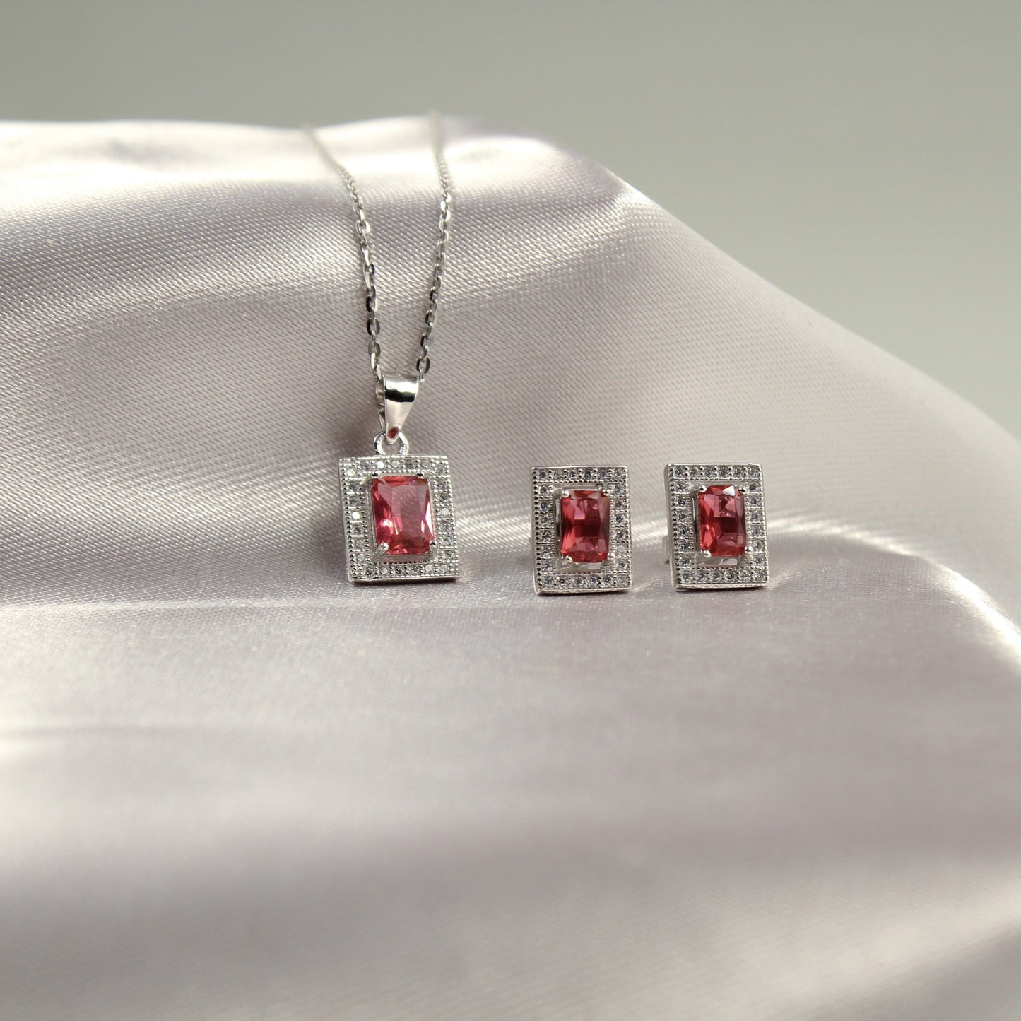 Conjunto de joyería de plata con piedra rosa, que incluye un collar y un par de aretes.
