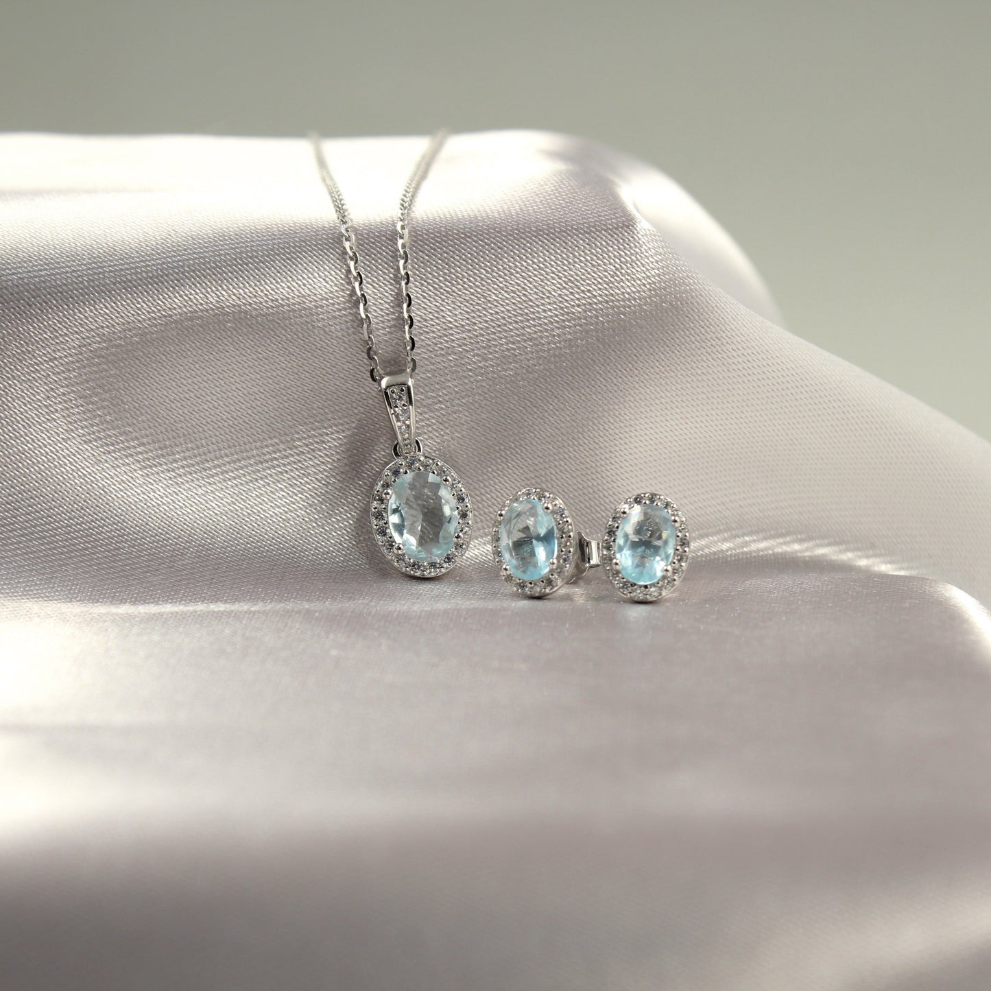 Juego de joyería con colgante y aretes de piedras preciosas azul claro.