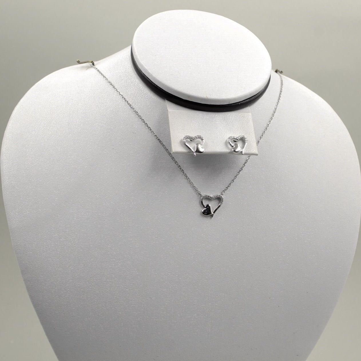 Juego de joyería con colgante y aretes de corazón plateado.