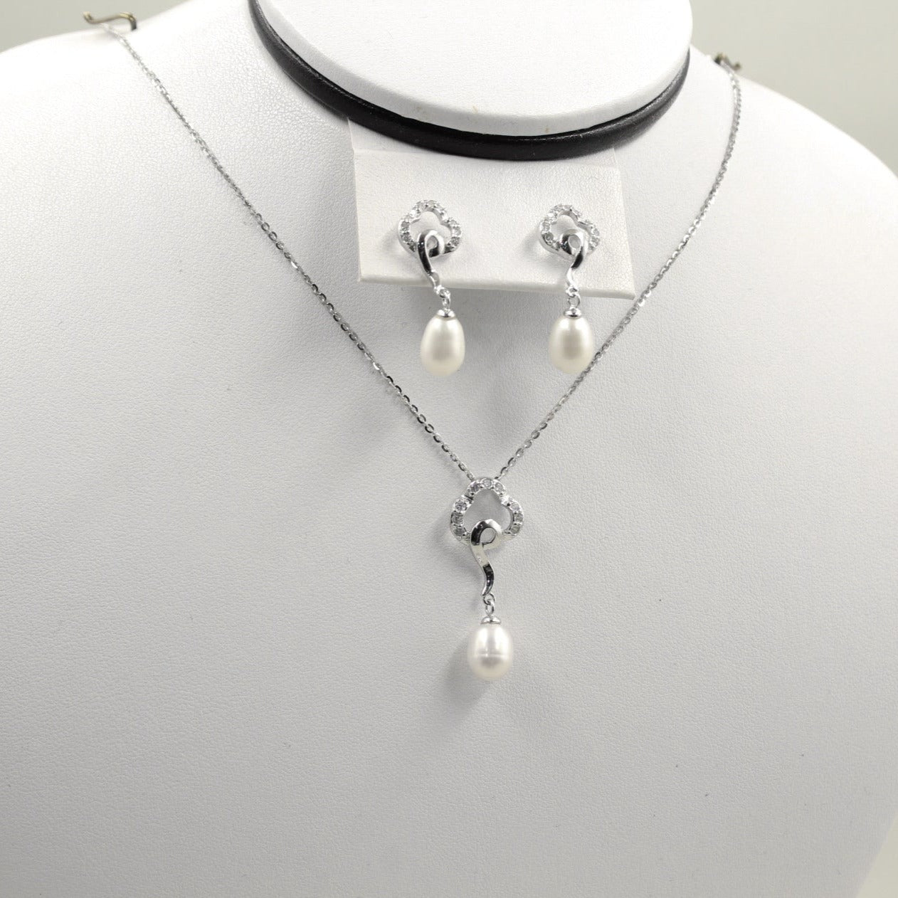 Juego de joyería con colgante y aretes de perla con detalles circulares.