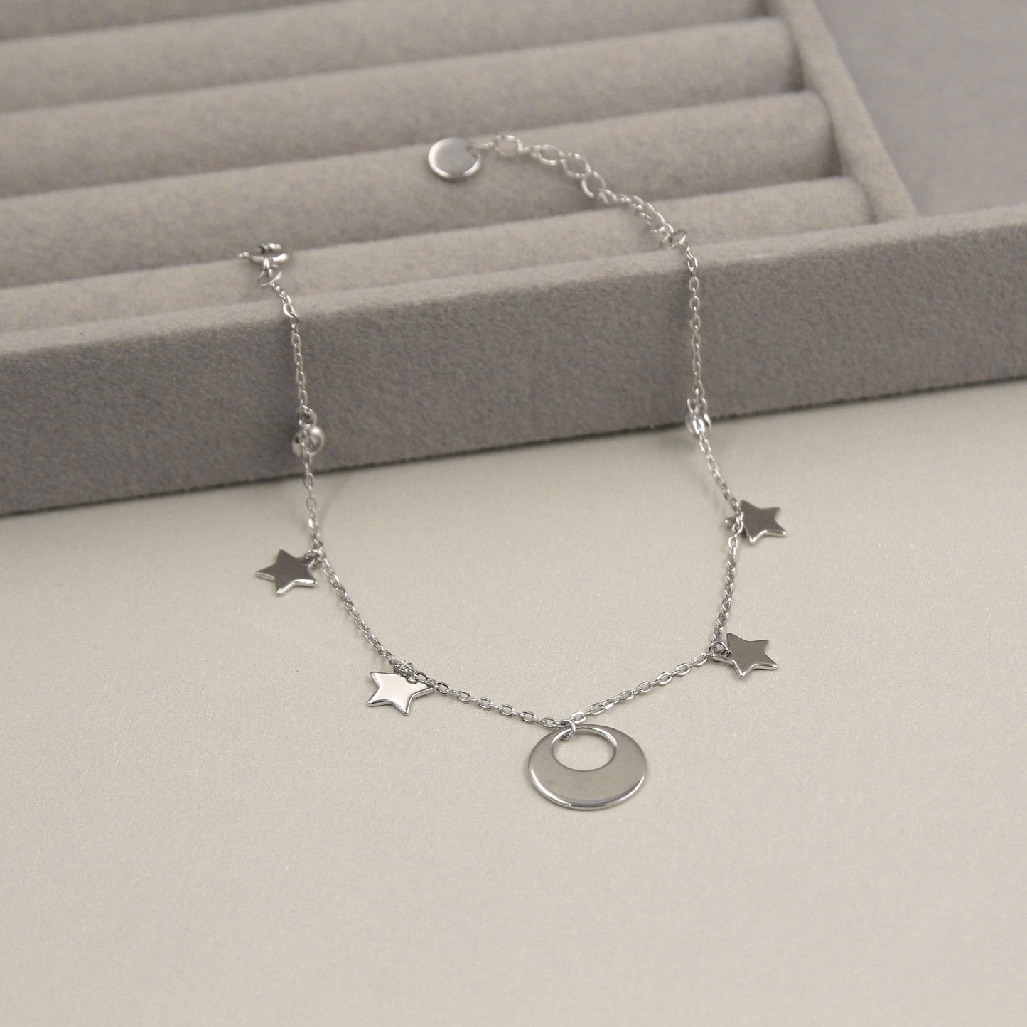 Pulsera de plata con cinco dijes de estrellas y un dije central en forma de luna.