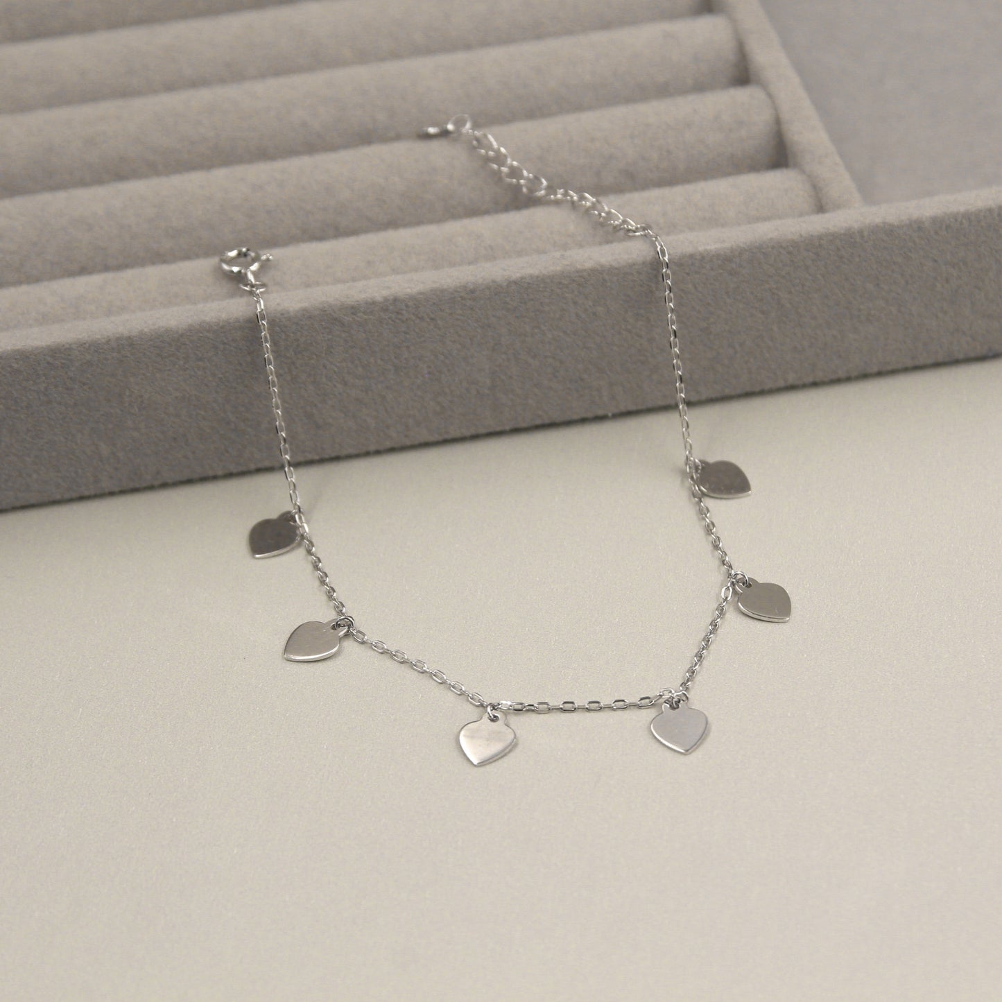 Pulsera de plata con seis dijes en forma de corazón.