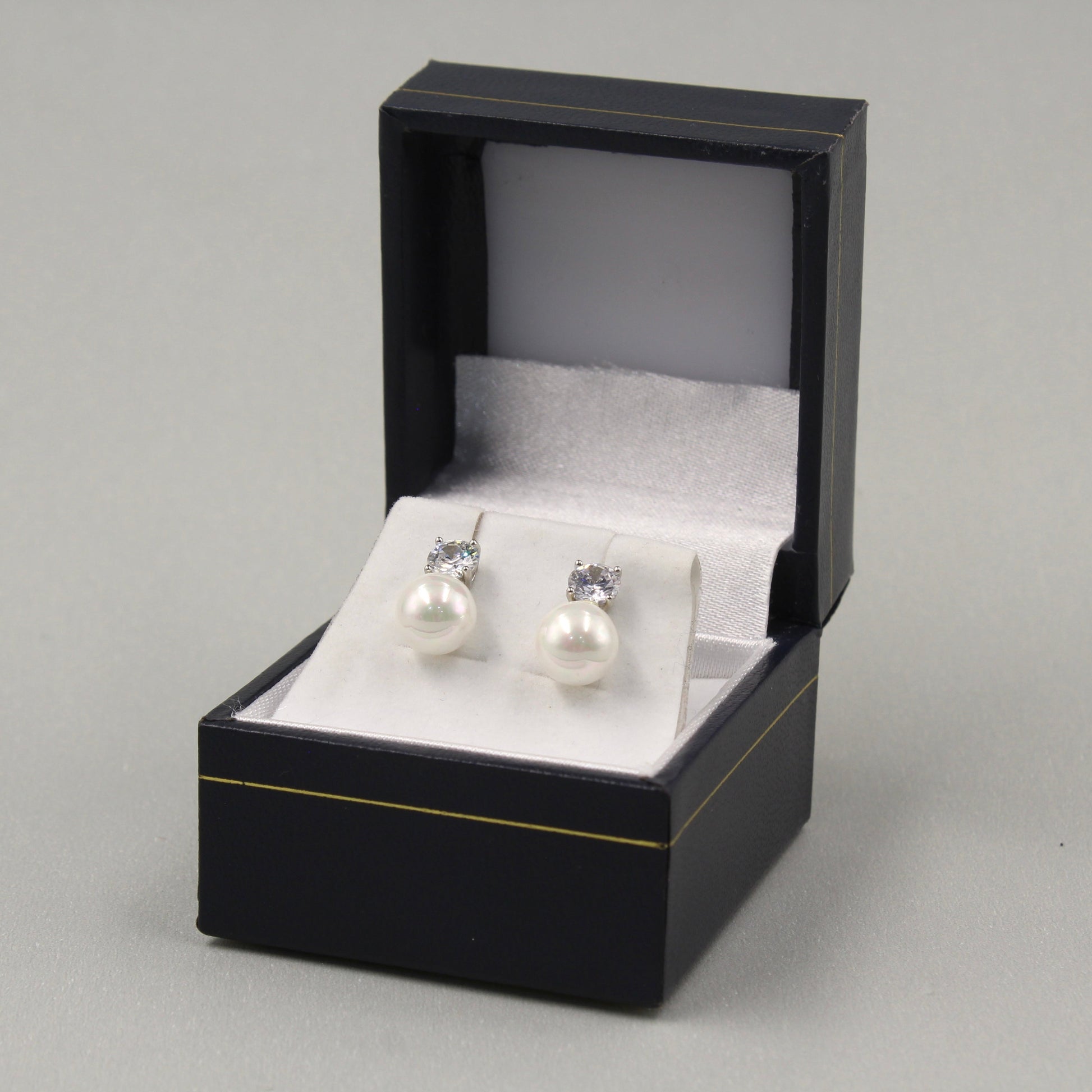 Pendientes de perlas con brillantes pequeños en una caja negra.