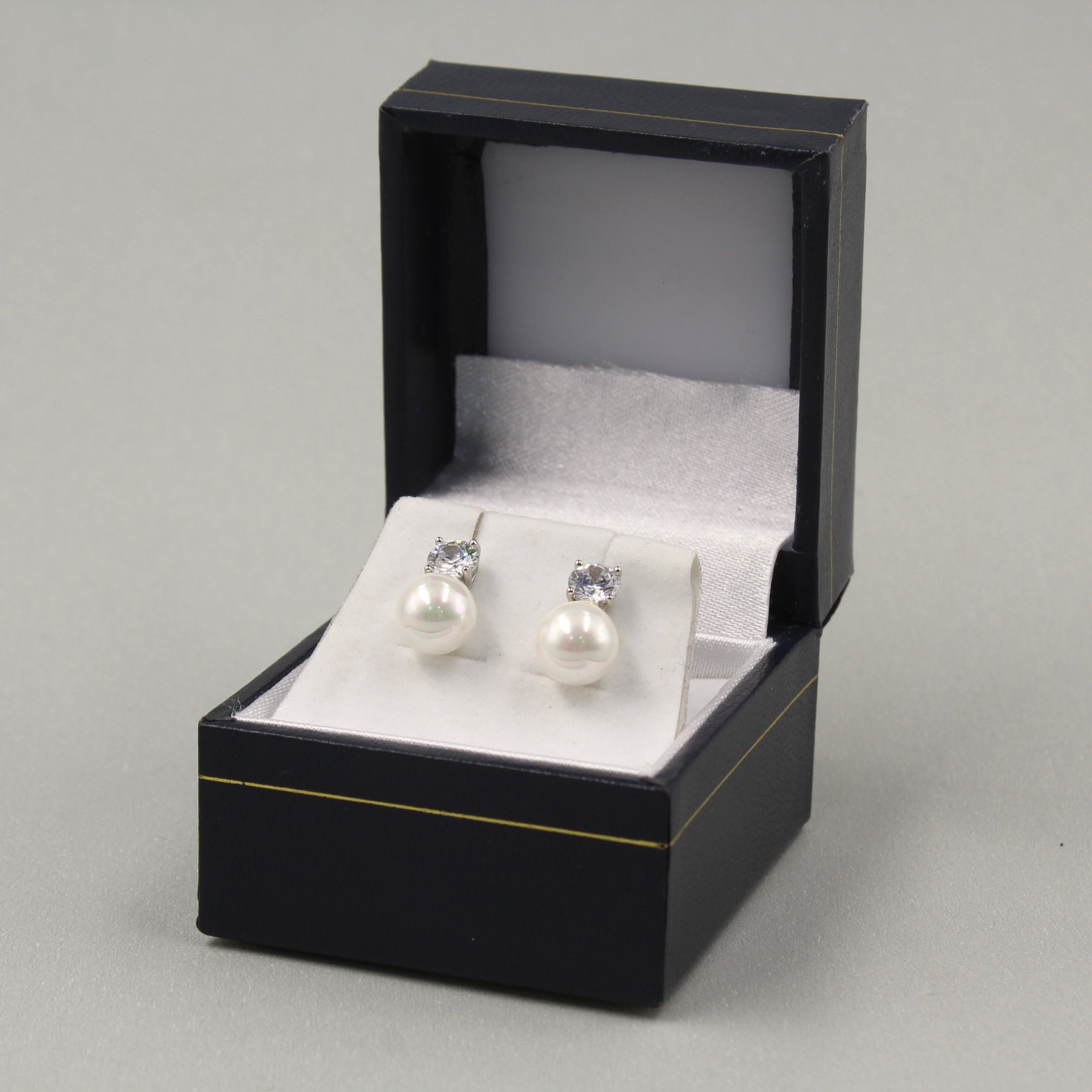 Pendientes de perlas con brillantes pequeños en una caja negra.