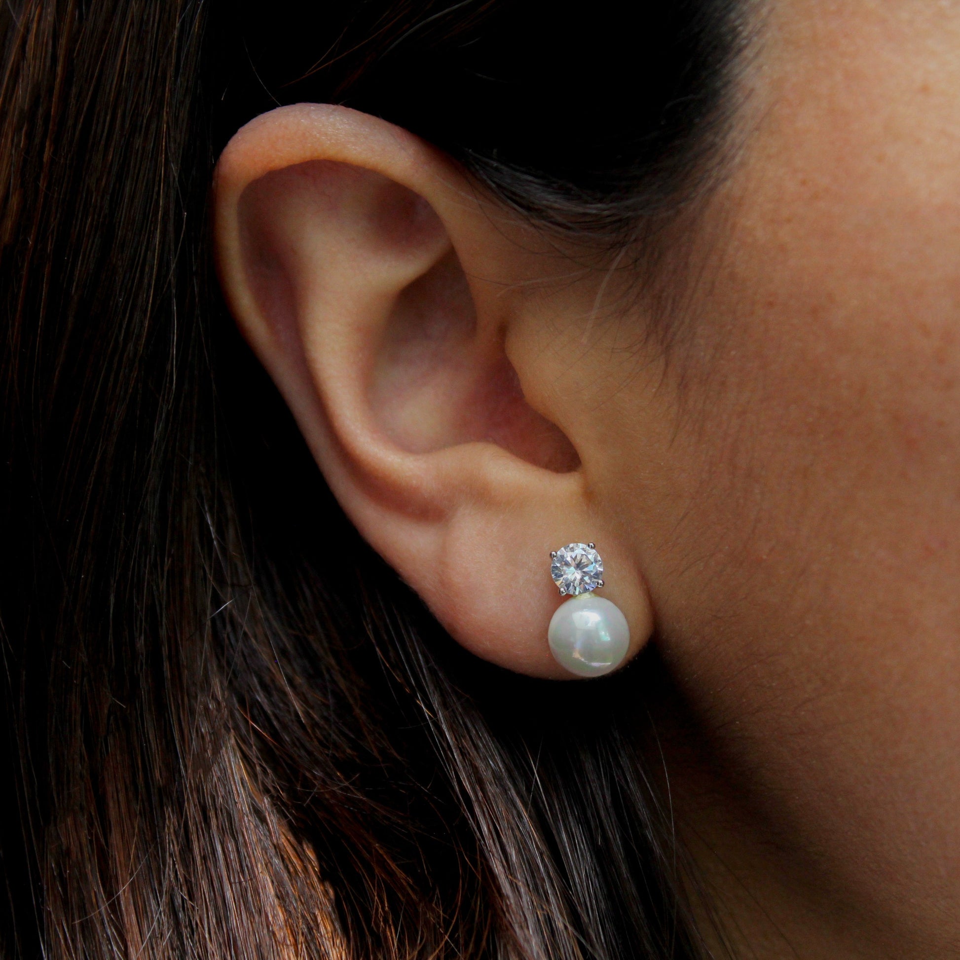 Mujer con aretes de perla con un brillante redondo.