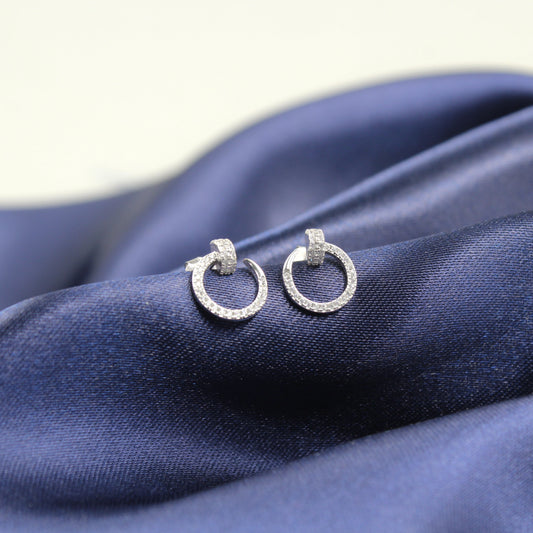 Aretes de argolla pequeña incrustados con diamantes sobre una tela azul marino.