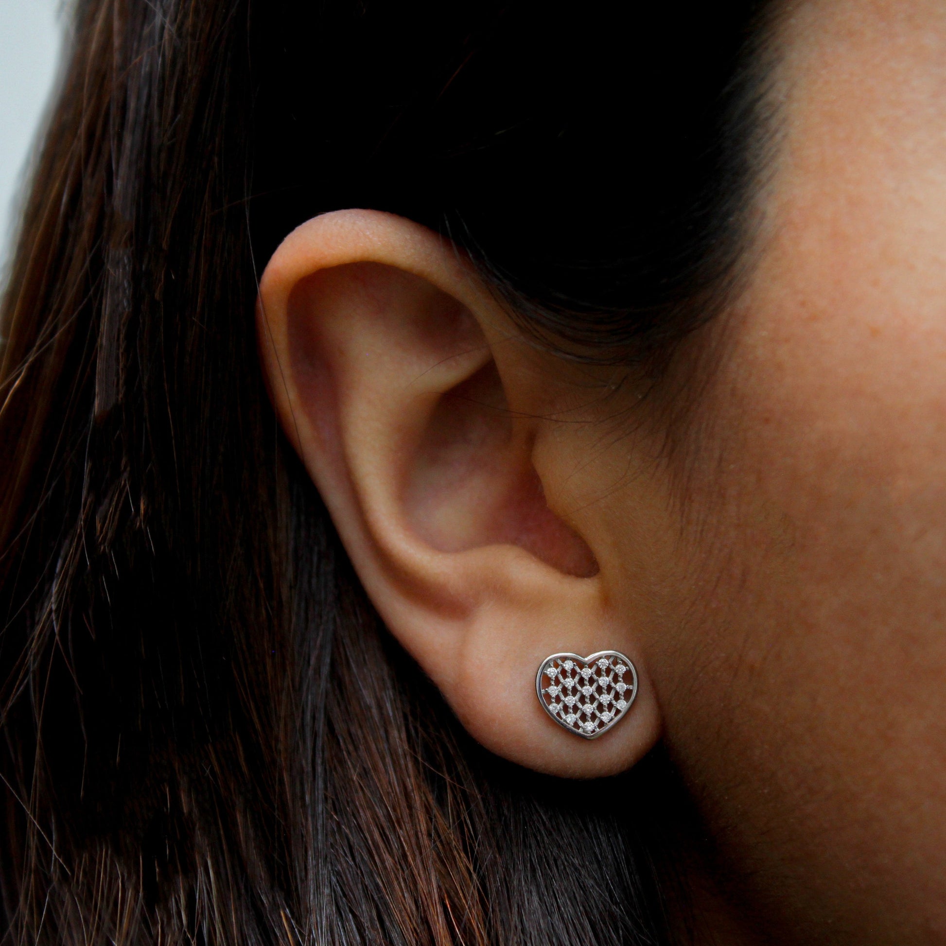 Una mujer joven con aretes de corazón incrustados de zirconia.