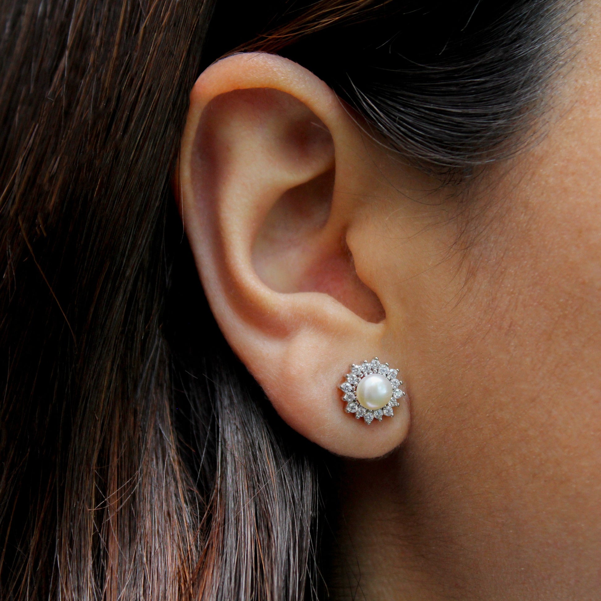 Mujer con aretes en forma de roseta con perla.