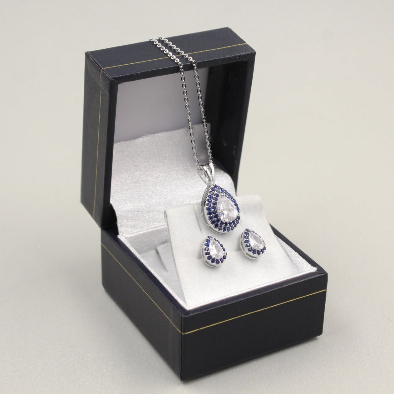 Juego de joyería con colgante y aretes en forma de luna y estrella, decorados con pequeños diamantes, presentado en una caja negra.