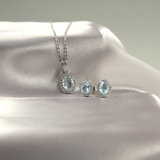 Juego de joyería con colgante y aretes de piedras preciosas azul claro.