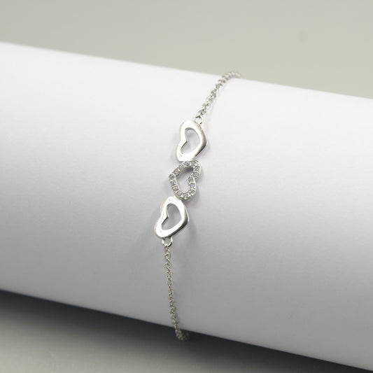 Pulsera de plata con tres dijes de corazones, uno de ellos adornado con pequeños diamantes.