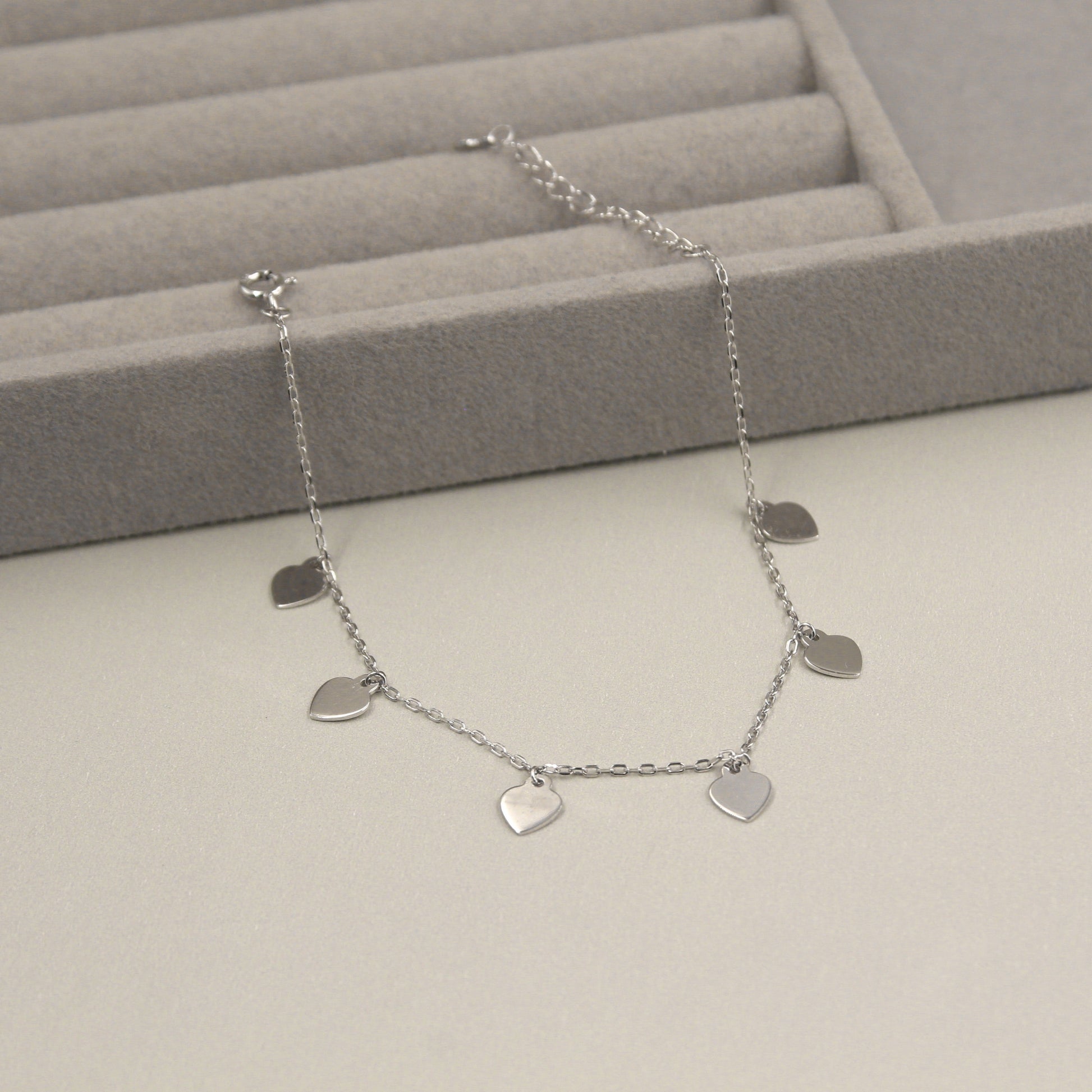  Pulsera de plata con seis dijes en forma de corazón.
