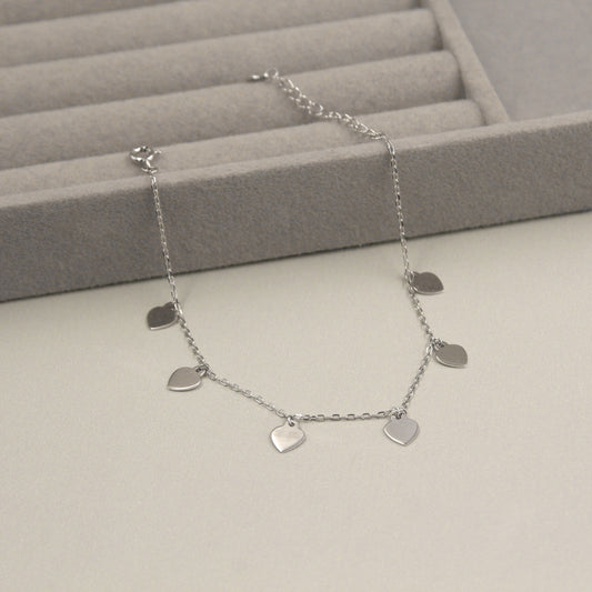  Pulsera de plata con seis dijes en forma de corazón.
