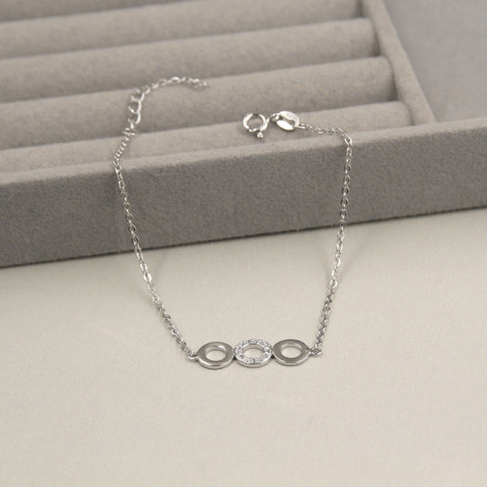 Pulsera de plata con tres dijes circulares, uno de ellos con pequeños diamantes.